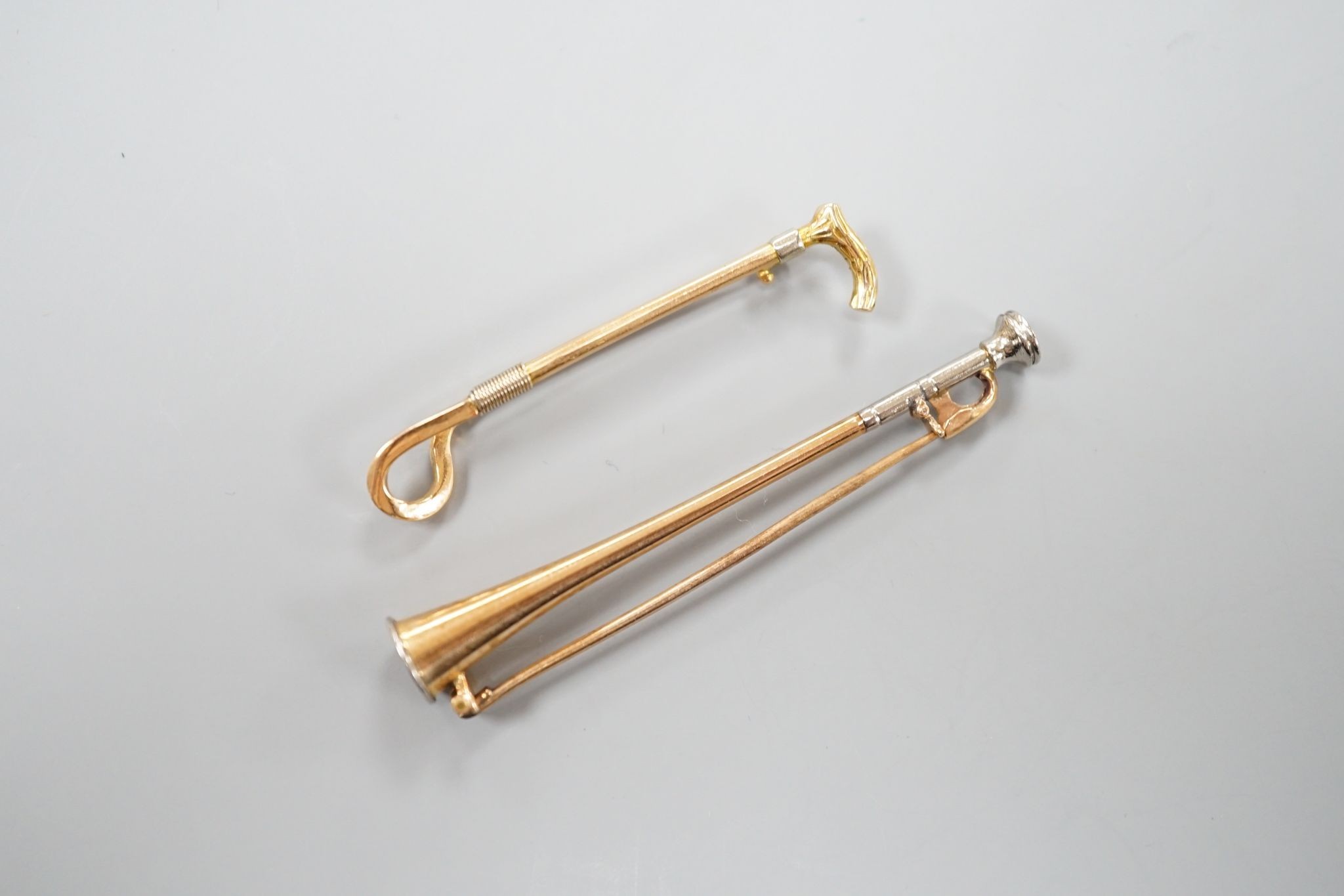 An Edwardian 15ct riding crop bar brooch, 44mm, 3.1 grams and a similar yellow and white metal hunting horn bar brooch, 56mm, gross 3.8 grams.